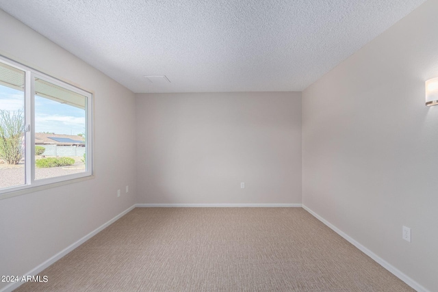 carpeted spare room with a textured ceiling and baseboards