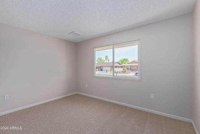 carpeted spare room featuring visible vents, baseboards, and a textured ceiling