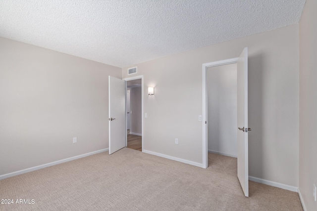 unfurnished bedroom featuring light colored carpet and a textured ceiling