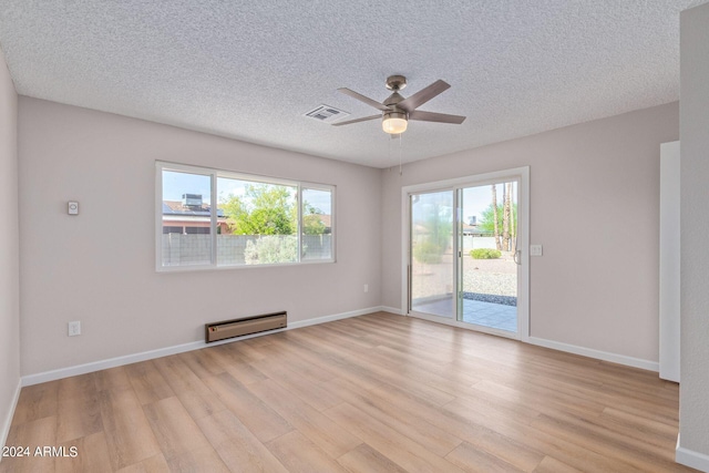 spare room with light wood finished floors, baseboards, visible vents, and baseboard heating