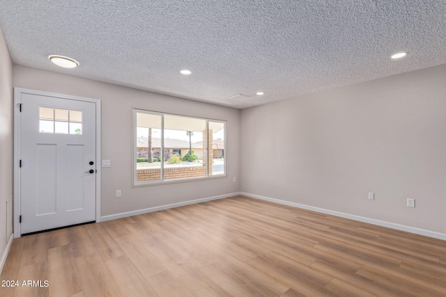 foyer with light wood-type flooring and a textured ceiling