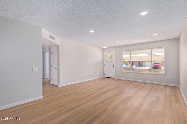 empty room with a textured ceiling and light wood-type flooring