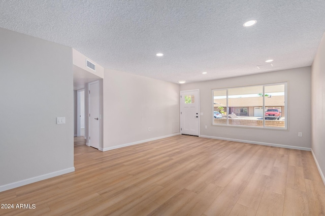 unfurnished room with recessed lighting, visible vents, light wood-style floors, a textured ceiling, and baseboards