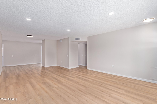 unfurnished room with a textured ceiling and light hardwood / wood-style floors