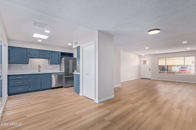 kitchen with stainless steel appliances, a sink, visible vents, light countertops, and blue cabinetry