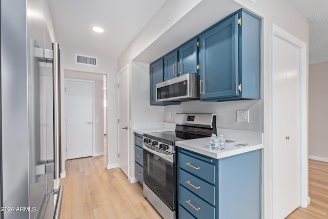 kitchen with visible vents, light wood-style floors, appliances with stainless steel finishes, light countertops, and blue cabinetry