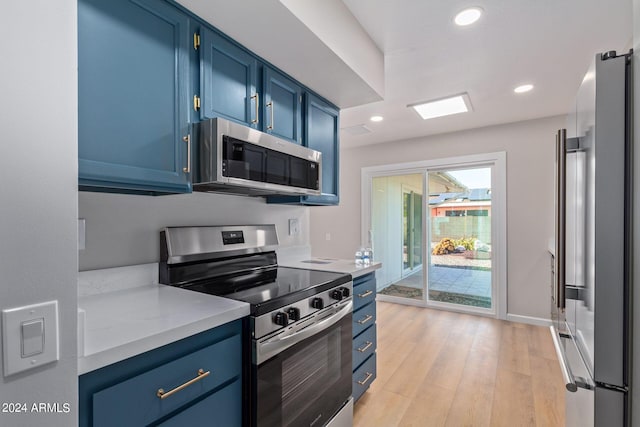 kitchen featuring appliances with stainless steel finishes, light countertops, blue cabinets, and light wood-style floors