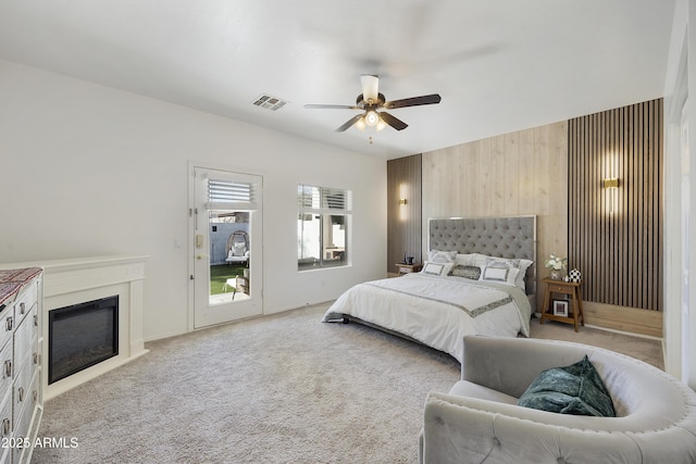 carpeted bedroom featuring ceiling fan and wooden walls