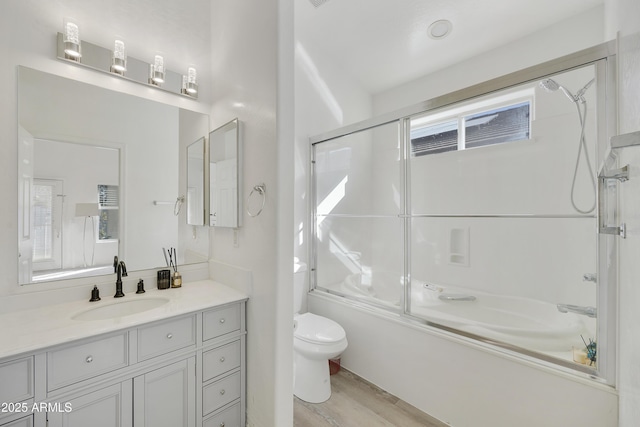 full bathroom with enclosed tub / shower combo, wood-type flooring, vanity, and toilet