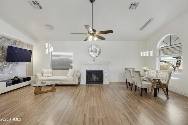 living room featuring vaulted ceiling, hardwood / wood-style floors, ceiling fan, and a fireplace