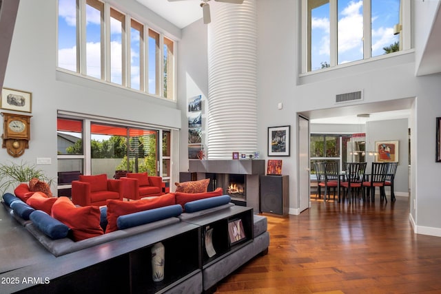 1209 W Golden Ln, Phoenix, AZ 85021 - living area featuring a multi sided fireplace, visible vents, hardwood / wood-style floors, a high ceiling, and baseboards