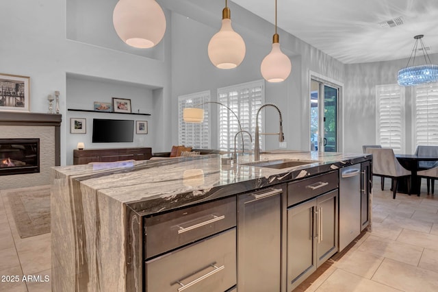 kitchen featuring sink, hanging light fixtures, light stone countertops, and light tile patterned flooring