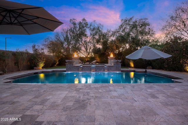 pool at dusk with a patio area, a hot tub, and an outdoor kitchen