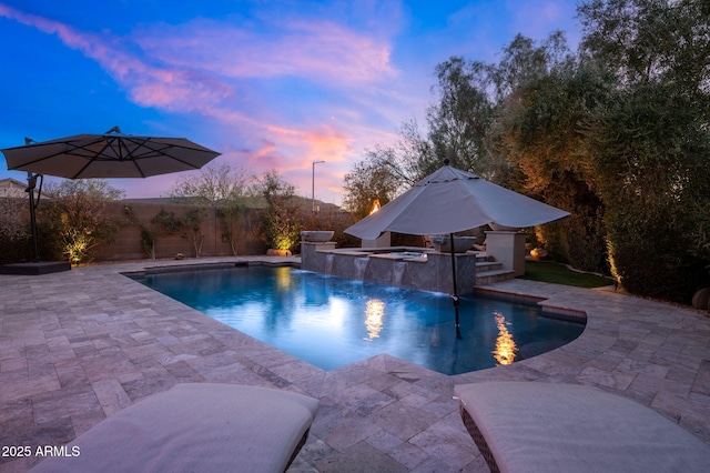 pool at dusk featuring pool water feature, a patio, and a jacuzzi