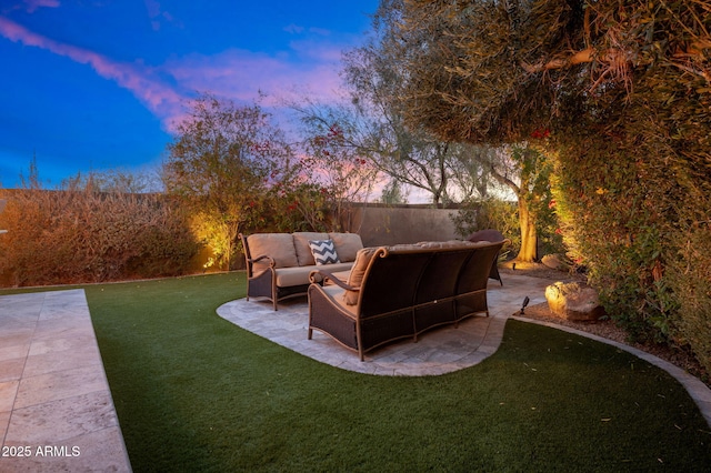 yard at dusk with an outdoor living space and a patio area