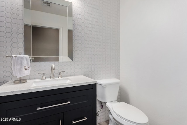 bathroom with vanity, toilet, and backsplash