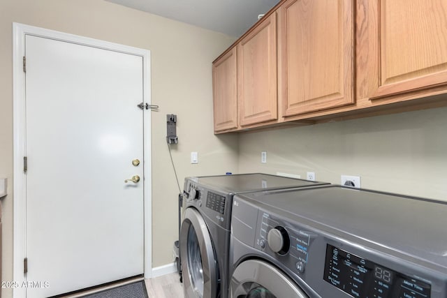 clothes washing area featuring cabinets and separate washer and dryer