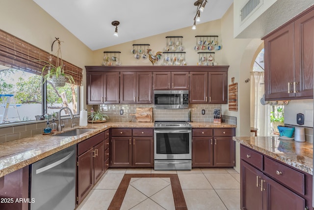 kitchen featuring appliances with stainless steel finishes, vaulted ceiling, backsplash, a sink, and visible vents