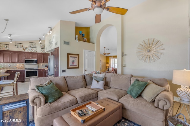 living room with light tile patterned flooring, ceiling fan, high vaulted ceiling, visible vents, and arched walkways