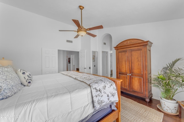 bedroom with high vaulted ceiling, a ceiling fan, visible vents, arched walkways, and wood finished floors