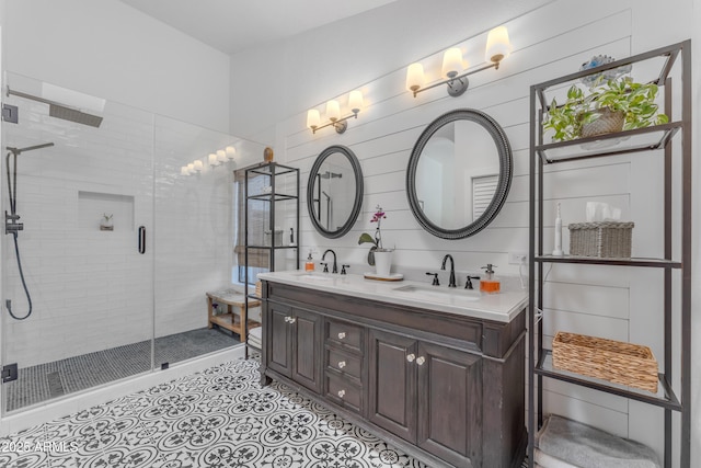 full bathroom with a stall shower, double vanity, and a sink