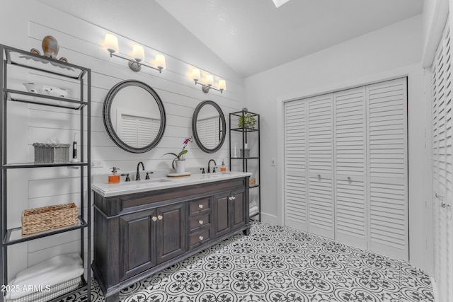 bathroom with a sink, double vanity, and lofted ceiling