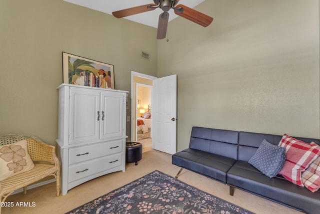 living room featuring a towering ceiling, a ceiling fan, visible vents, and light colored carpet