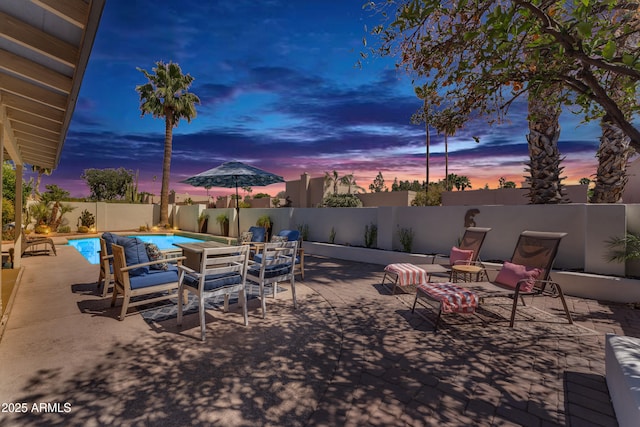 patio terrace at dusk featuring a fenced backyard and a fenced in pool