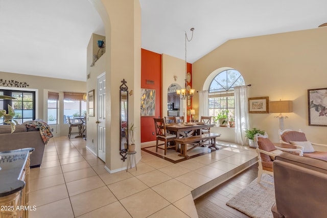 living area featuring a chandelier, arched walkways, baseboards, light tile patterned flooring, and high vaulted ceiling