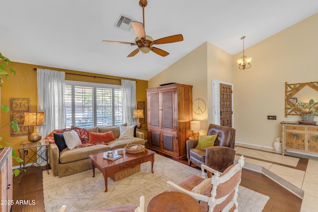 living area with visible vents, baseboards, light wood-type flooring, high vaulted ceiling, and ceiling fan with notable chandelier