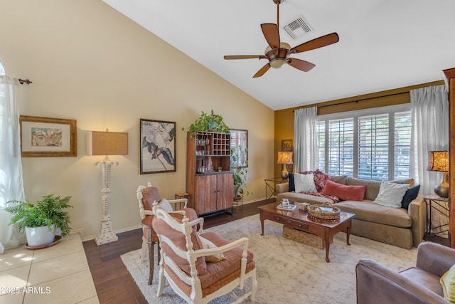 living area with visible vents, ceiling fan, baseboards, wood finished floors, and high vaulted ceiling