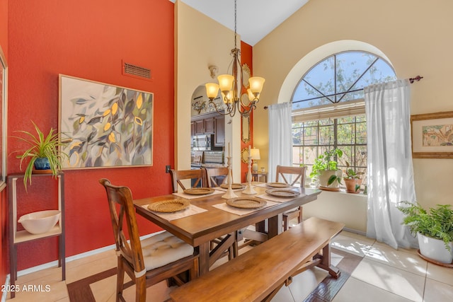 tiled dining space featuring an inviting chandelier, visible vents, and high vaulted ceiling