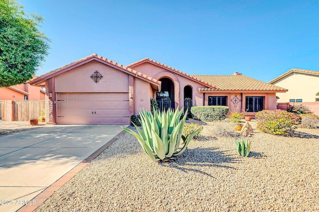 mediterranean / spanish-style home featuring stucco siding, fence, concrete driveway, an attached garage, and a tiled roof