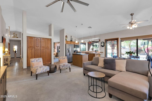 living room featuring light carpet, visible vents, ceiling fan with notable chandelier, and high vaulted ceiling