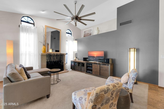 living room with visible vents, light carpet, high vaulted ceiling, and a ceiling fan