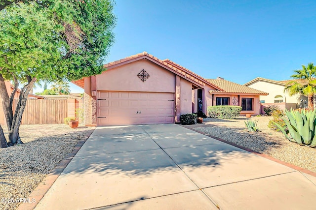 view of front of house with fence, driveway, stucco siding, a garage, and a tile roof