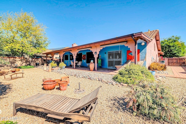 back of property featuring stucco siding, a patio area, fence, and a chimney