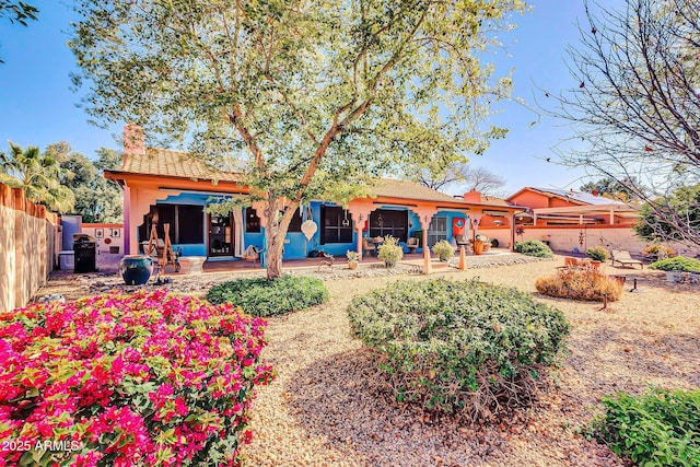 back of property with a patio, fence, stucco siding, a chimney, and a tile roof