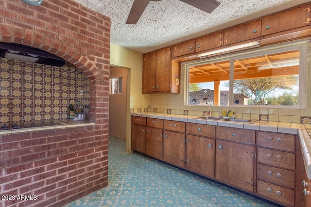 kitchen featuring brick wall, black electric cooktop, ceiling fan, and sink