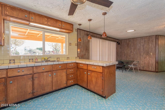 kitchen featuring kitchen peninsula, pendant lighting, ceiling fan, carpet floors, and sink