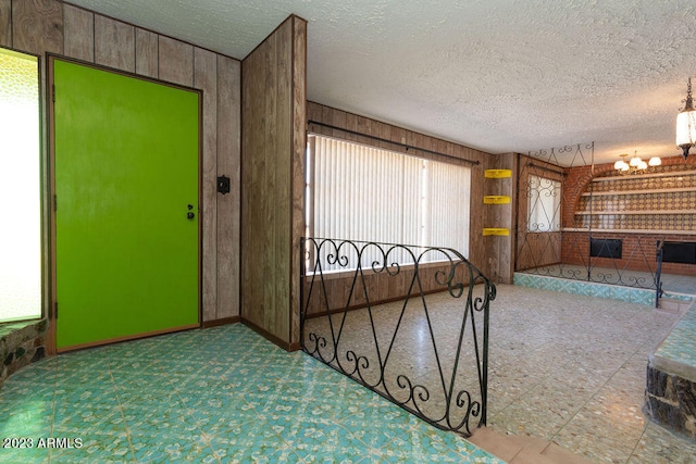 interior space featuring a textured ceiling, wooden walls, and a healthy amount of sunlight