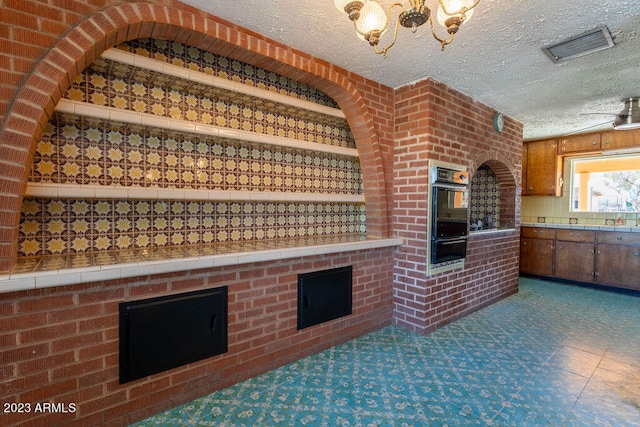 wine cellar featuring dark tile floors, a fireplace, a textured ceiling, and brick wall