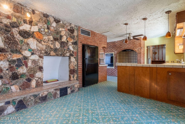 kitchen featuring pendant lighting, tile counters, dark colored carpet, and black fridge