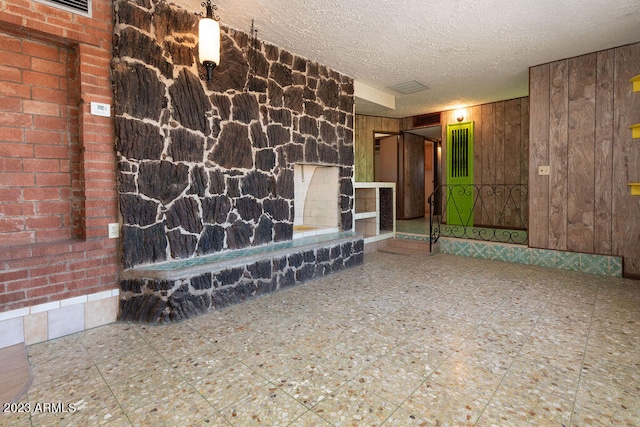 unfurnished room featuring wooden walls, tile flooring, and a textured ceiling