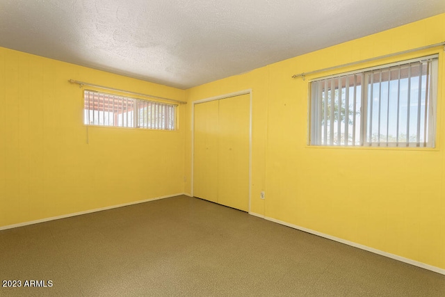 unfurnished room featuring a textured ceiling and dark colored carpet