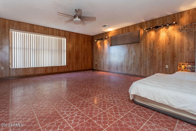 unfurnished bedroom featuring wooden walls, ceiling fan, and a textured ceiling