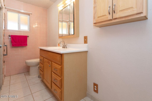 bathroom with tile flooring, toilet, vanity, and tile walls