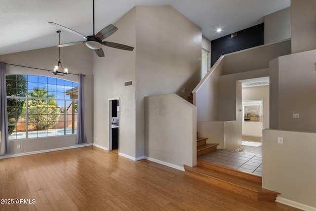 4753 E Bighorn Ave, Phoenix, AZ 85044 - unfurnished living room featuring high vaulted ceiling, stairs, wood finished floors, ceiling fan, and a chandelier