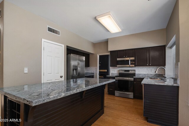 4753 E Bighorn Ave, Phoenix, AZ 85044 - kitchen featuring appliances with stainless steel finishes, tasteful backsplash, light wood-style floors, a sink, and light stone counters