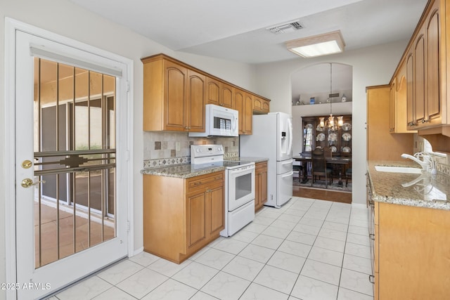 8431 W Utopia Rd, Peoria, AZ 85382 - kitchen featuring white appliances, arched walkways, decorative backsplash, light stone countertops, and healthy amount of natural light